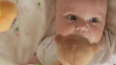Üstten Görünüm şirin bebek beşik içinde yalan ve taddy ayı oyuncaklar iplik seyir emzik ile vurdu. Bebek etrafına bakıyor ve sonra gülümsüyor ve gülüyor. Çocuk, ebeveyn sevgi ve eksikliği bakmakta kavramı