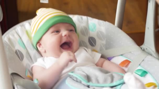 Fröhliche kleine niedliche Baby-Boy-Schaukel in elektrischer Schaukel im Wohnzimmer. — Stockvideo