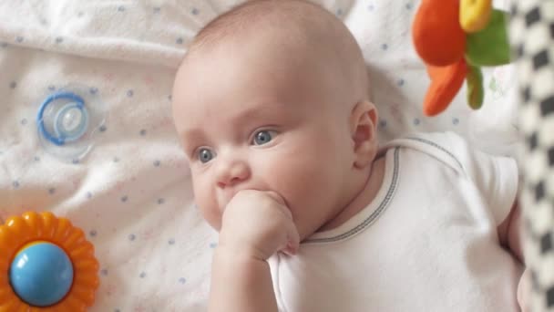 Baby Sucking Fingers, Closeup. 4K UltraHD, UHD The look of the baby in the camera close up shot. A cute little baby is looking into the camera. The baby looks around and then smiles and laughs — Stock Video