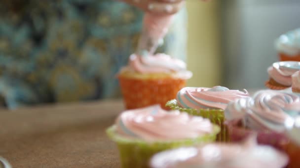Mladé dívky zdobení cup dort se smetanou a berry pomocí vaření tašku, poprášená multicolor koláčky pro stranu. Záběr rukou Zenske dávat máslo krém na chutné dorty, domácí pekárna