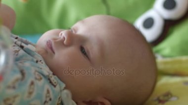 Bebek playimat üzerinde yatıyor ve mutlu çocuk playmat tatlı gülümseyen bir oyuncakla oynar