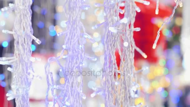 Guirnaldas blancas de Navidad oscilan y brillan por la tarde, una cámara lenta golpeando la parte superior e inferior, borroso, bokeh — Vídeos de Stock