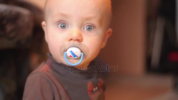 A cute little baby is looking into the camera and is not happy big gray eyes angrily looks at the camera and starts smiling 4k slow motion shot — Stock Video