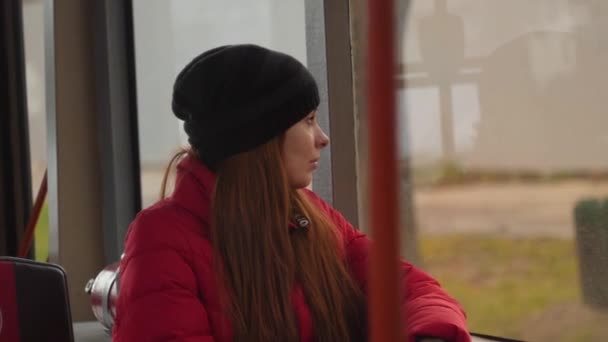 Молодая грустная женщина начинает плакать в автобусе в облачный дождливый день. Она смотрит в мокрое окно и грустит. Одиночество в большом городе. Медленное движение — стоковое видео