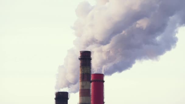 Air pollution from industrial enterprises. Pipes that throw smoke in the sky, lay the power lines in the foreground. A large factory in the background of the city. 4K, slow motion — Stock Video