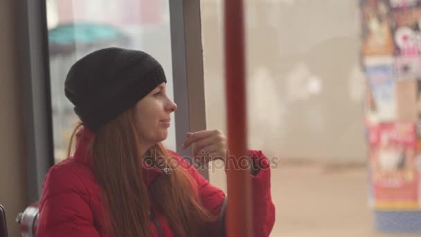 Joven mujer triste montando un autobús en un día lluvioso aburrido. Ella mira por la ventana mojada y está triste. Soledad en la gran ciudad. Movimiento lento — Vídeos de Stock