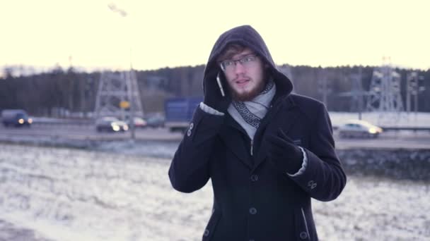 Een jonge man met bril emotioneel gesprekken en vloeken op de telefoon — Stockvideo