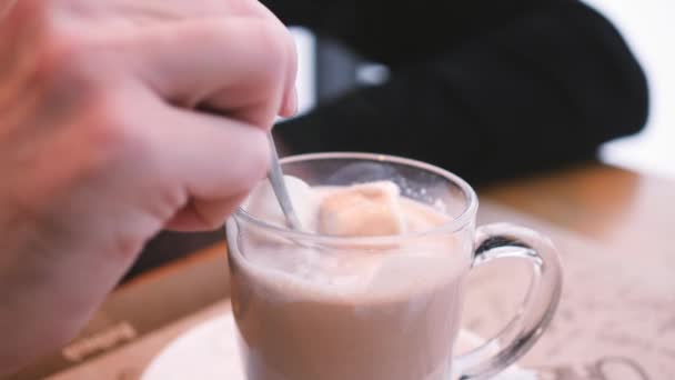 Chocolate caliente en un café. revuelva el chocolate caliente con malvavisco en una taza con paredes transparentes — Vídeos de Stock