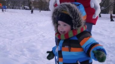 Yıl eski yürüyüş ve having fun kış Park'ta sıcak kar elbiseli erkek bebek. Kışın ilk karda oynarken çocuk.