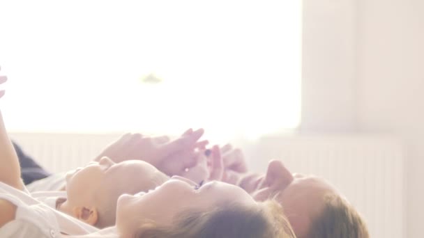 Niño feliz con los padres cosquillas en la cama en casa — Vídeos de Stock