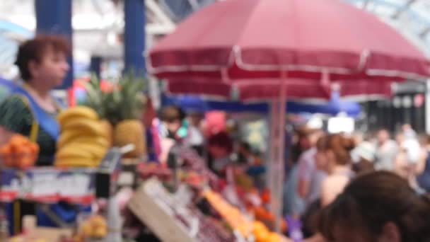 Desfocado pessoas irreconhecíveis vídeo de fundo do balcão de frutas no mercado da cidade no dia de verão com vista lateral câmera lenta em 4K — Vídeo de Stock