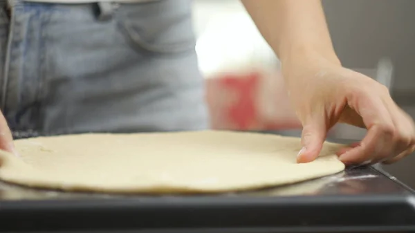 Pizza kochen. Der Koch bereitet den Pizzateig zu. Ein Mann oder eine Frau ist mit der Zubereitung einer leckeren Pizza beschäftigt — Stockfoto