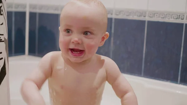 Bebé niño divirtiéndose en baño sonriendo y jugando con su madre que detrás de la cámara en cámara lenta de tamaño medio filmado 4K . — Foto de Stock