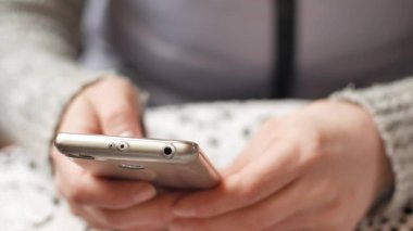 Akıllı telefon dokunmatik ekran KEY- yakın çekim kullanan bir iş kadını, Parmaklar yazıya dokunur ve modern akıllı telefon ekranını kaydırır.