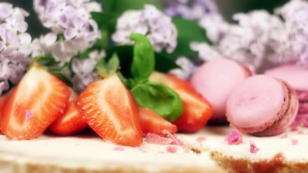 Kuchen mit einem Ausschnitt verziert mit Makronen, Erdbeeren und Blumen, 4k slow mo close up — Stockvideo