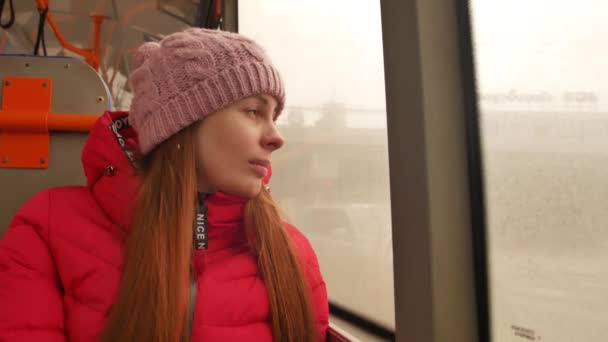 Close-up shot of a young sad woman traveling by bus on a dull rainy day. She looking out the wet window and breathing heavily. Loneliness in a big city — Stock Video