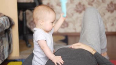 Küçük çocuk yerde sırtüstü yatan babasıyla oynuyordu. Çocuk babasına gülümserken mutlu olur ve anne eli oğluna çekiç verir. 4k video 'da ön görünüm orta görüntüsü.