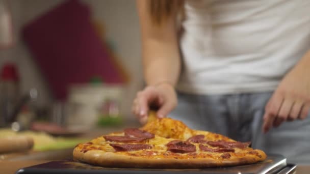 Woman chef with a wooden spatula lifts hot freshly prepared pepperoni pizza with cheese over a baking sheet. Top view time lapse 4K video. — 비디오
