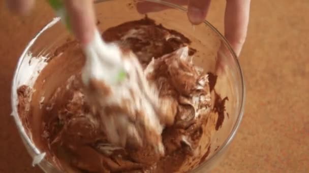 A woman chef hands are kneading cream and cocoa in a deep glass bowl in the manufacture of chocolate cream for baking a cake. Top view slow motion 4K video. — 비디오