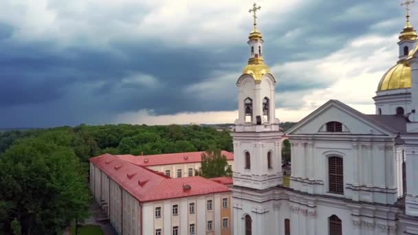 Beautiful aerial cityscape panoramic view with a river and a cathedral with a gilded roof in the foreground and city buildings and looming storm in summer day on background. Drone view shot in 4K. — Stock Video
