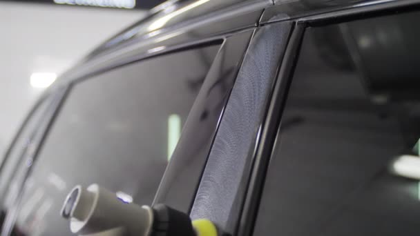 Arbetare man polerar en svart bil dörrar med en speciell anordning i en biltvättstation. 4k slow motion närbild video. — Stockvideo
