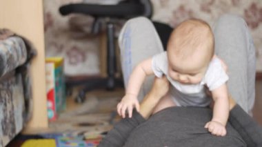 Baba, yerde yatıyor, göğsünde oturan oğluyla oynuyordu. Çocuk babasına bakıp mutlu bir şekilde kameraya bakıyordu. 4k video 'da ön görünüm orta görüntüsü.