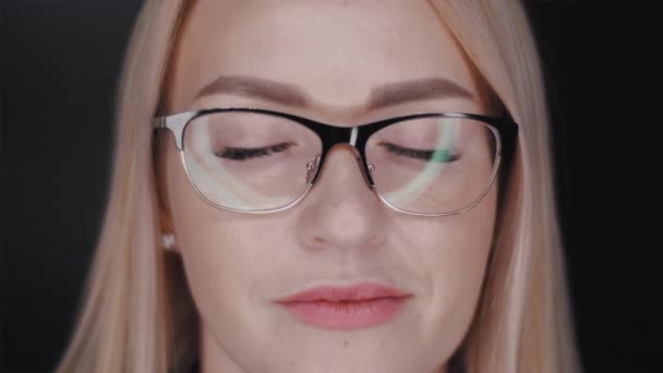 Close-up portret van een mooie jonge blonde haar zakenvrouw met een bril die staan met gesloten ogen en dan openen en zelfverzekerd kijkt in de camera. Slow motion vooraanzicht video in 4k. — Stockvideo