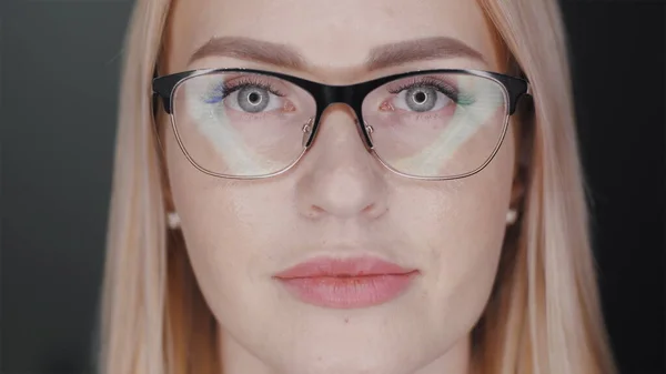 Mulher de negócios de cabelo loiro atraente em óculos está olhando para a câmera e sorri para mostrar aparelho de dentes em pé no fundo preto. Conceito de tratamento ortodôntico. Slowmotion close-up retrato 4K vídeo — Fotografia de Stock