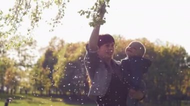 Genç anne kucağında güneşte parkta bir bebek tutar.