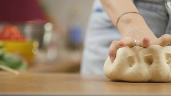 Mujer en la mesa de la cocina hace pizza de comida doméstica, manos de trabajo y empujando agitar amasar la masa, enfoque selectivo dolly shot —  Fotos de Stock