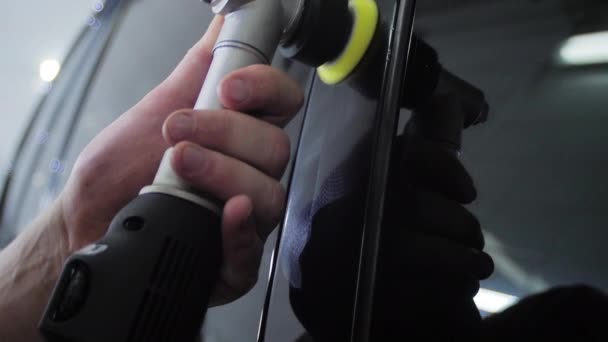 Polerowanie czarnego samochodu ze specjalnym urządzeniem w myjni samochodowej. — Wideo stockowe