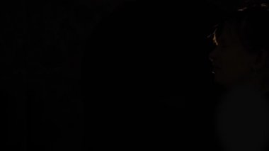 Kadın silueti elinde bir peçeteye hapşırıyor ve arka planda siyah bir ışık görüyor. Hastalık belirtisi olarak hapşırmak ya da alerjik hapşırma konsepti. Şekil kenar görünümü yavaş çekim 4K video.