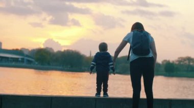 Anne, bebeğin elini tutuyor. Anne ve oğlu gezinti güvertesinde yürüyorlar.