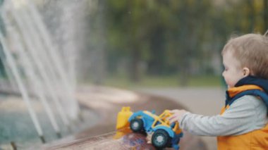 Çocuk parktaki çeşmede oynuyor. Çocukların neşesi, mutlu bir çocukluk. Aile değerleri