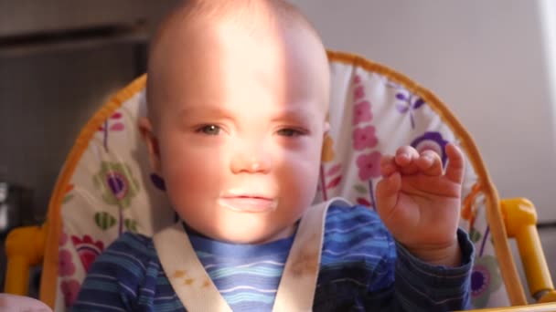 Pequeño retrato de bebé carismático que mira a la cámara y luego estornuda en un rayo de luz solar en su cara 4K lento mo — Vídeo de stock