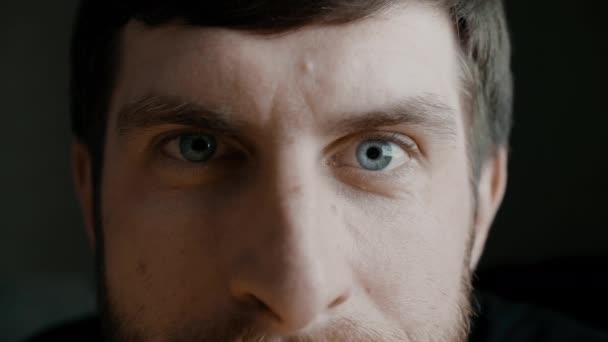 青い虹彩の目でカメラを見ている若い髭の男は、笑顔と彼の眉毛を移動します。健康的な視力の概念。スローモーションフロントビューポートレート4Kビデオを閉じます. — ストック動画