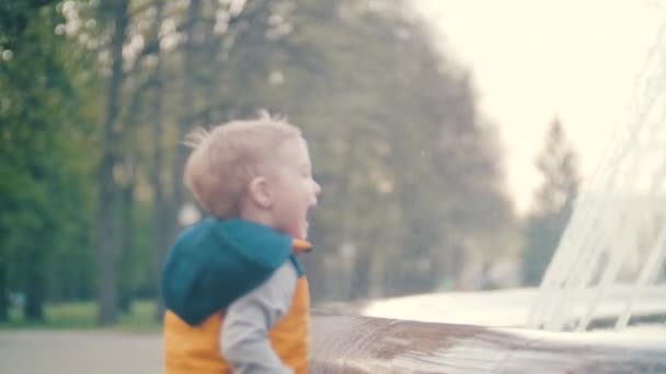 Malý chlapec hraje na fontánu v parku — Stock video