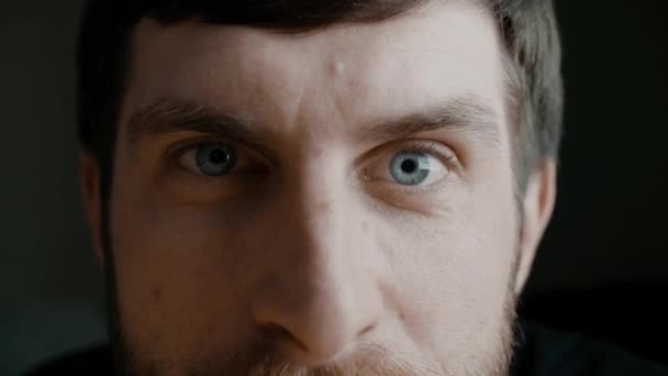 Jeunes hommes barbus iris bleu yeux macro shot. L'homme regarde la caméra et cligne des yeux. Concept de vision saine. Vue frontale au ralenti gros plan vidéo 4K . — Video