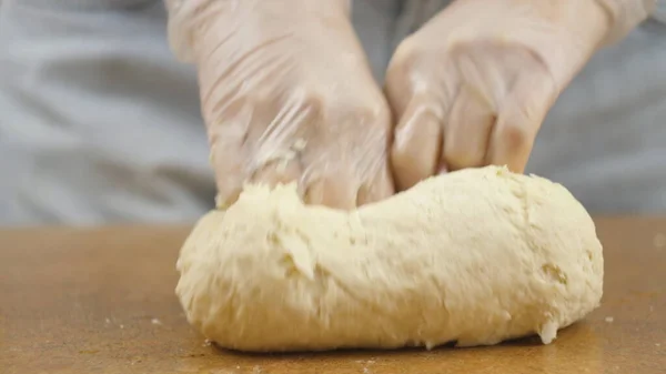 Vrouw moeder of dochter op de keukentafel maakt huishoudelijk voedsel pizza, handen werken en duwen roer kneed het deeg, selectieve focus dolly schot — Stockfoto