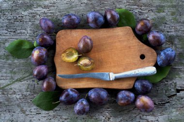 Ahşap tahta ve bıçak etrafında olgun Erik