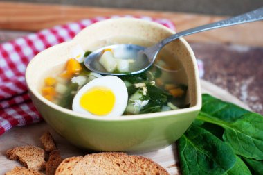 Yeşil borç, kızkuşu, maydanoz, yumurta ve ızgara kalp şeklinde ahşap arka planda kaşıkla