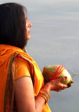  Hindu kadın, 27 Ekim 2017 'de Hyderabad, Hindistan' da düzenlenen geleneksel Chhas Puja ayini sırasında, gün batımında, göl kıyısında Tanrı 'ya dua etmek için yiyecek sunuyor.