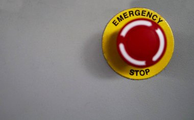 Endüstriyel bir makinenin kontrol panelinde acil durdurma düğmesi ya da kırmızı düğmenin yakın görüntüsü                               