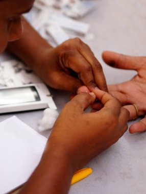 17.2019 Nisan 'ında Hyderabad, Hindistan' da kan şekerini ölçmek için hastanın parmağını neşterle delen doktor.