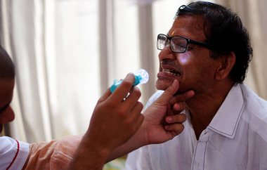 Doktor, 17 Nisan 2019 'da Hyderabad, Hindistan' daki bir tıp kampında Hintli bir adamın ağız sağlığını kontrol edin.