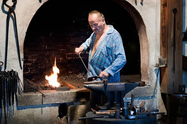 Herrero trabajando metal en el yunque en la fragua — Foto de Stock