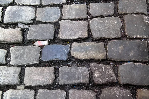 Мощеная каменная дорога правильной формы, абстрактный фон старого мощеного тротуара крупным планом — стоковое фото