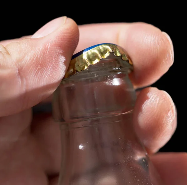 Glass bottle with a cap in his hand on a black background — Stock Photo, Image