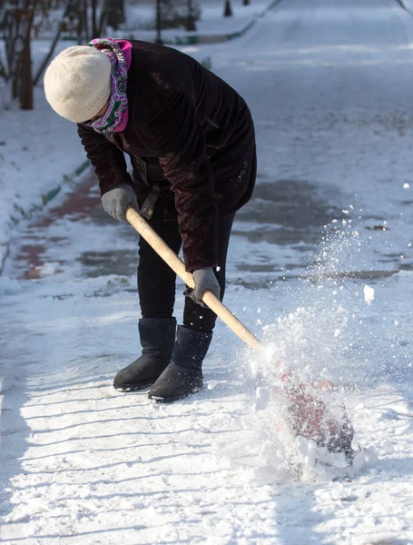 Working woman cleans snow shovel in the nature — Stock Photo, Image