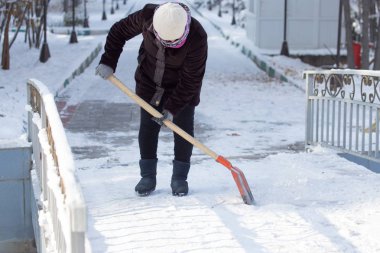çalışan kadın kar küreği doğada temizler